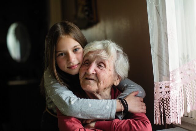 Young girl hugging elderly mother.