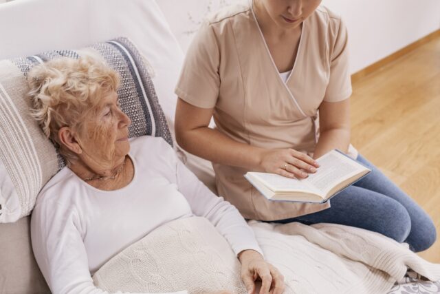 Girl reading to elderly patient.